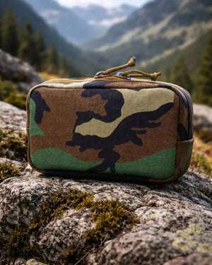 Woodland camouflage fanny pack on a rock with mountains in the background.