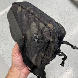 Fanny pack with woodland camouflage pattern, black strap, and visible zippers.