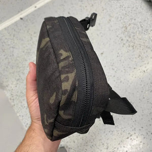 Fanny pack with woodland camouflage pattern and black zipper.
