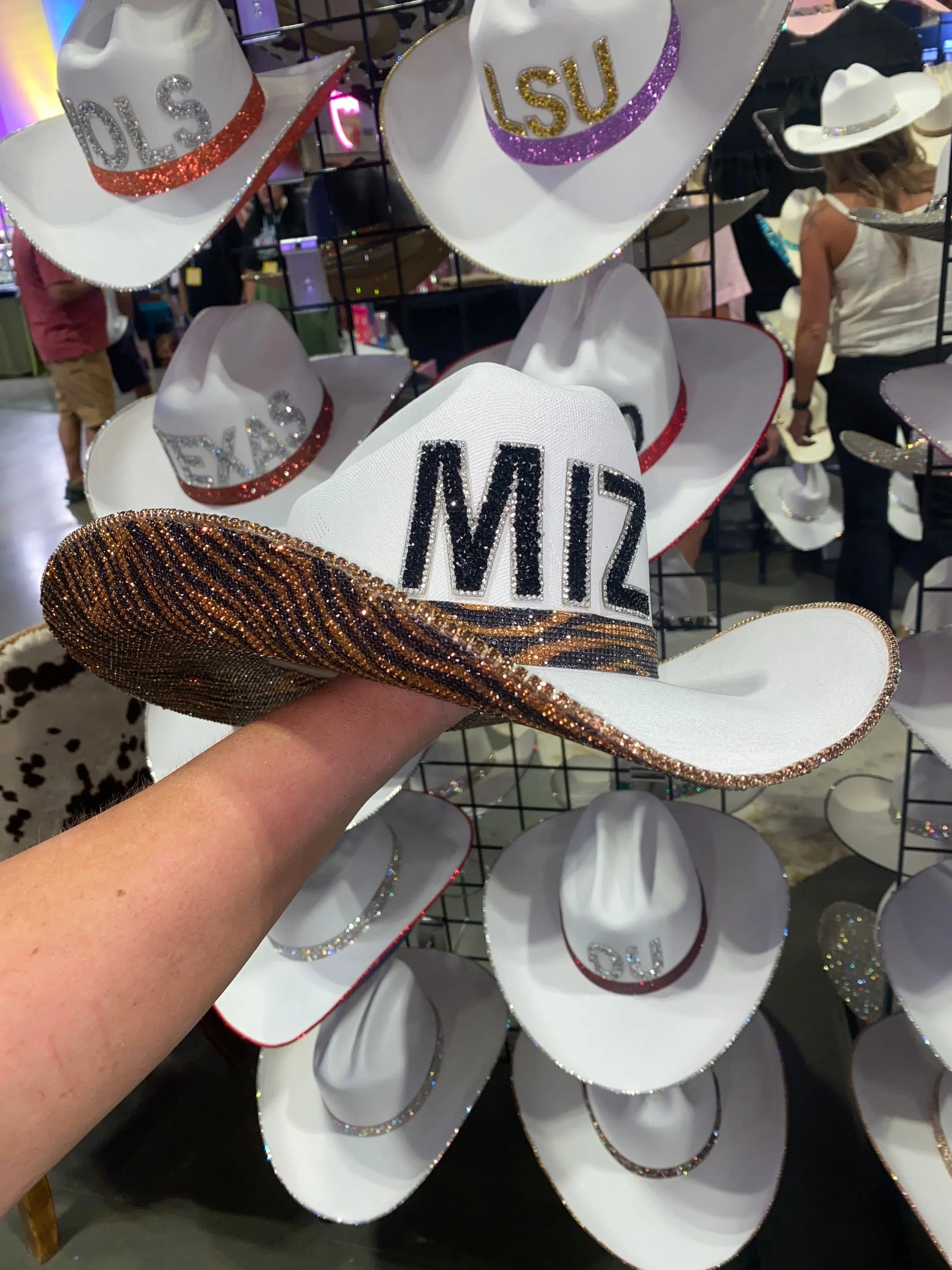 White cowboy hat with black MIZ rhinestone letters and tiger print band.