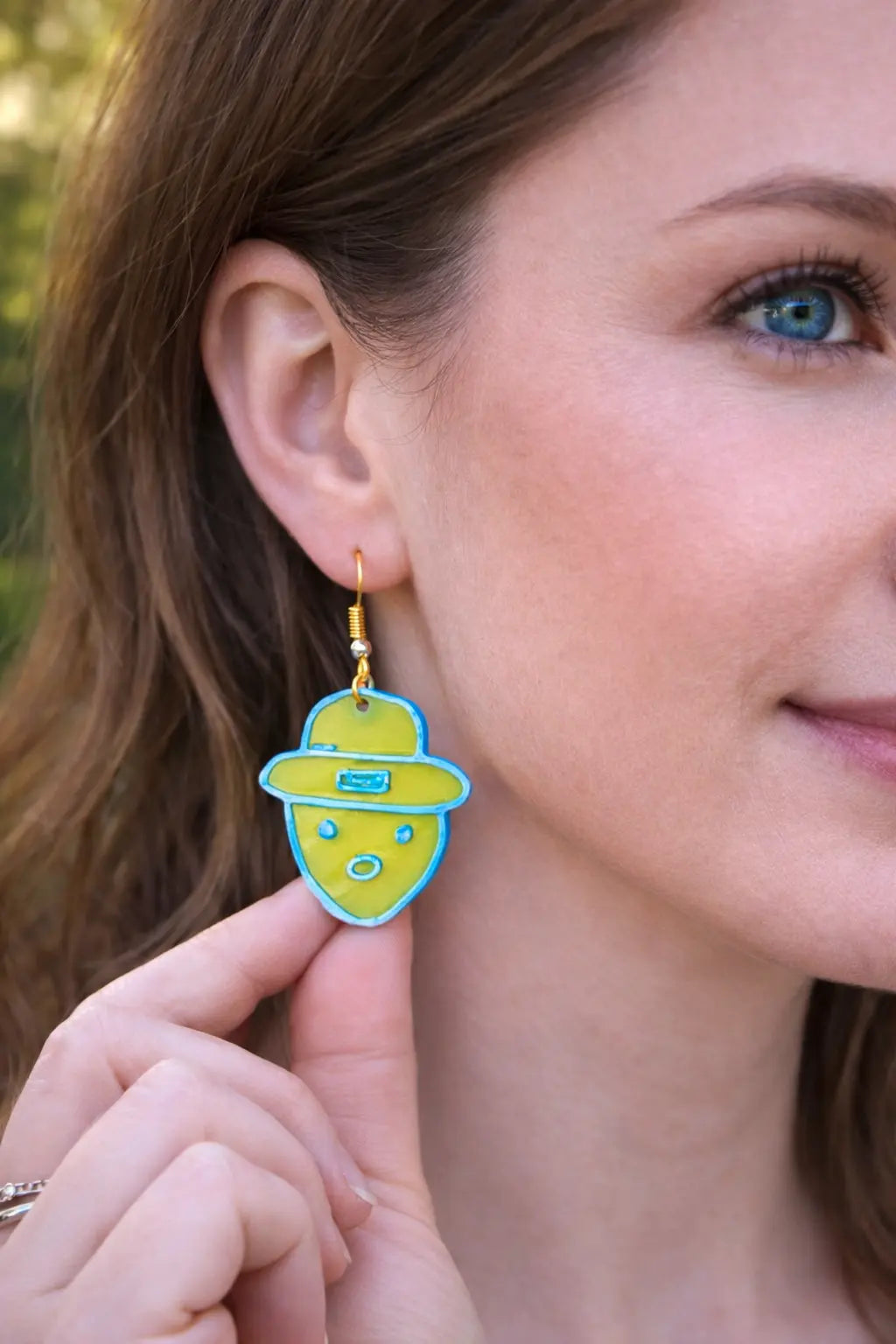 Woman with green & blue leprechaun earring handmade by kids at The Tween Space.