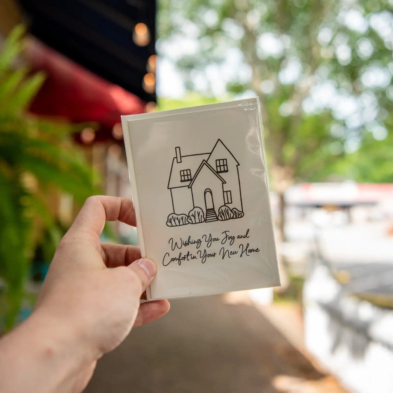 Person holding a new home greeting card with a house illustration and text