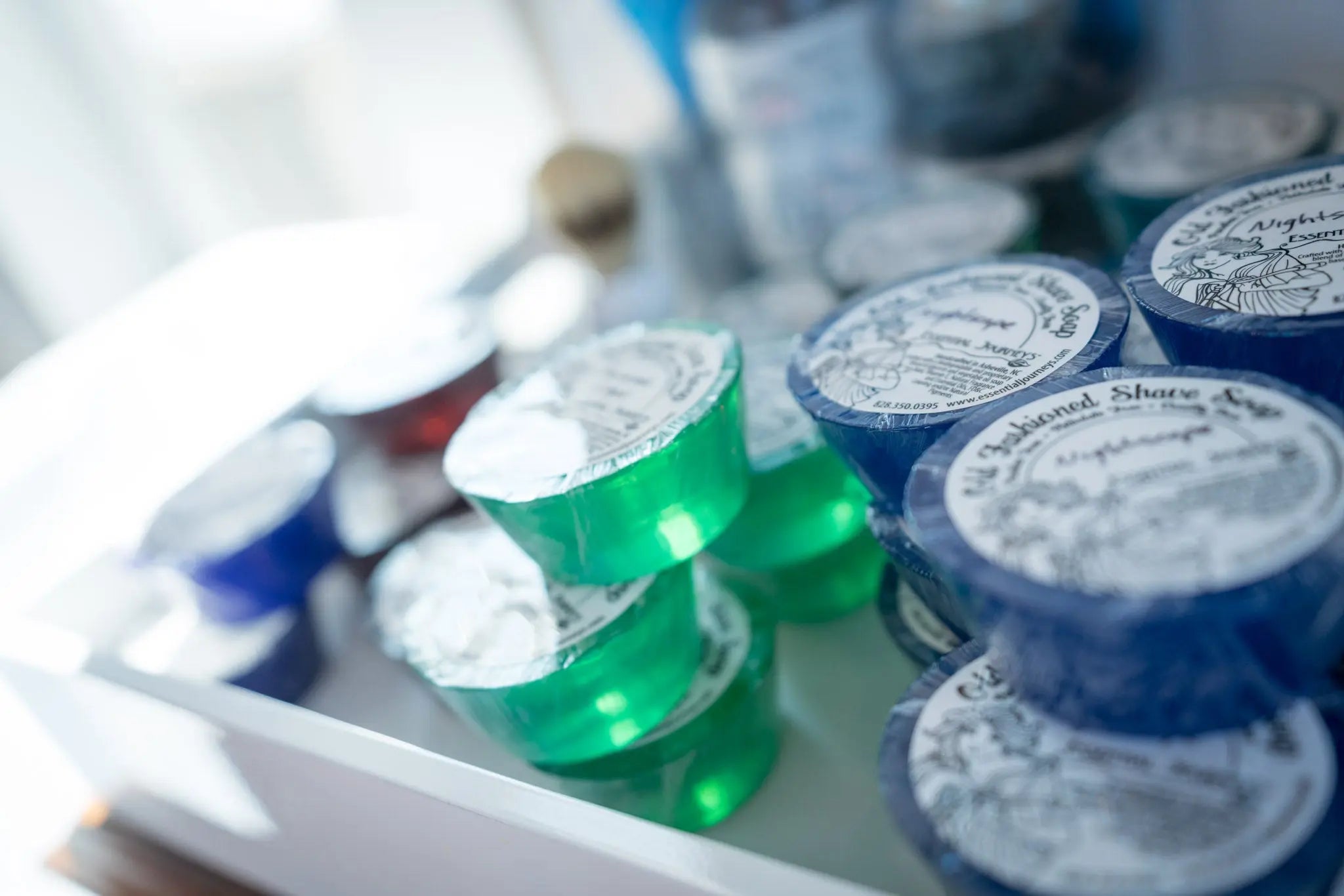 Essential Journeys old fashioned shave soaps in green and blue stacked in a tray.