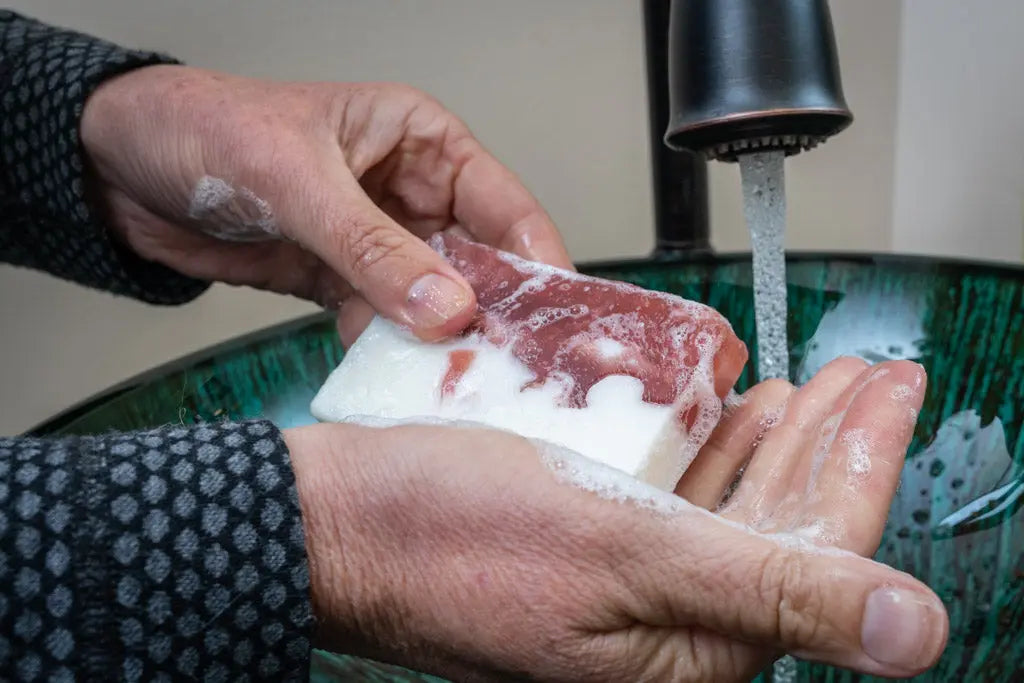 Hands washing with peppermint goat milk soap slice under running water