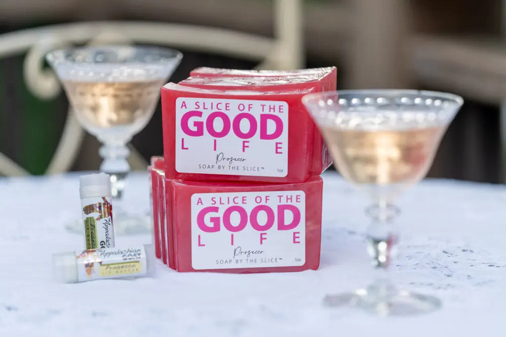 Pink prosecco scented soap bars and lip balm with champagne glasses.