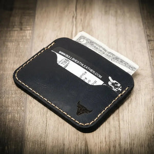 Black leather minimalist card wallet with stitched edges and a bull logo.
