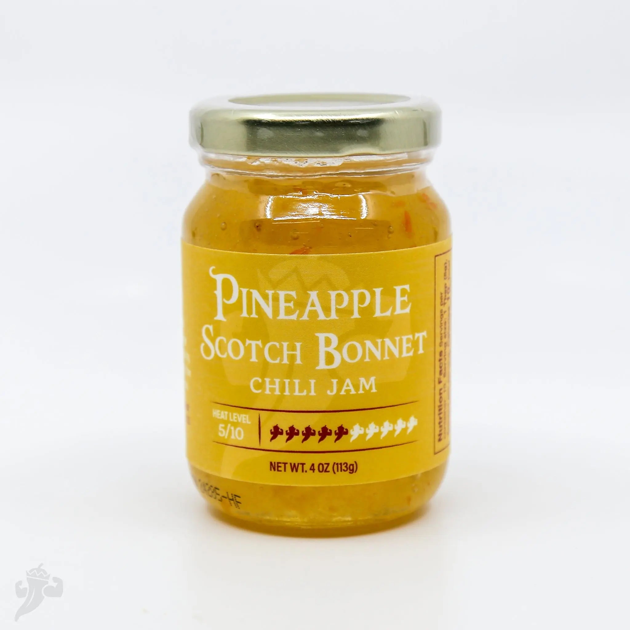 Pineapple Scotch Bonnet Chili Jam in a clear glass jar with a yellow label.