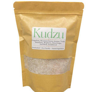 A kraft paper bag filled with granular laundry detergent, labeled "Kudzu" and listing ingredients like Grapefruit and Sandalwood.