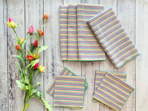 Set of four rainbow striped seersucker cloth napkins with artificial flowers.
