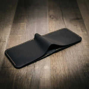 Black leather bifold wallet on a wooden surface.