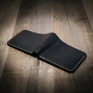Dark blue leather bifold wallet with embossed bull logo on wood surface