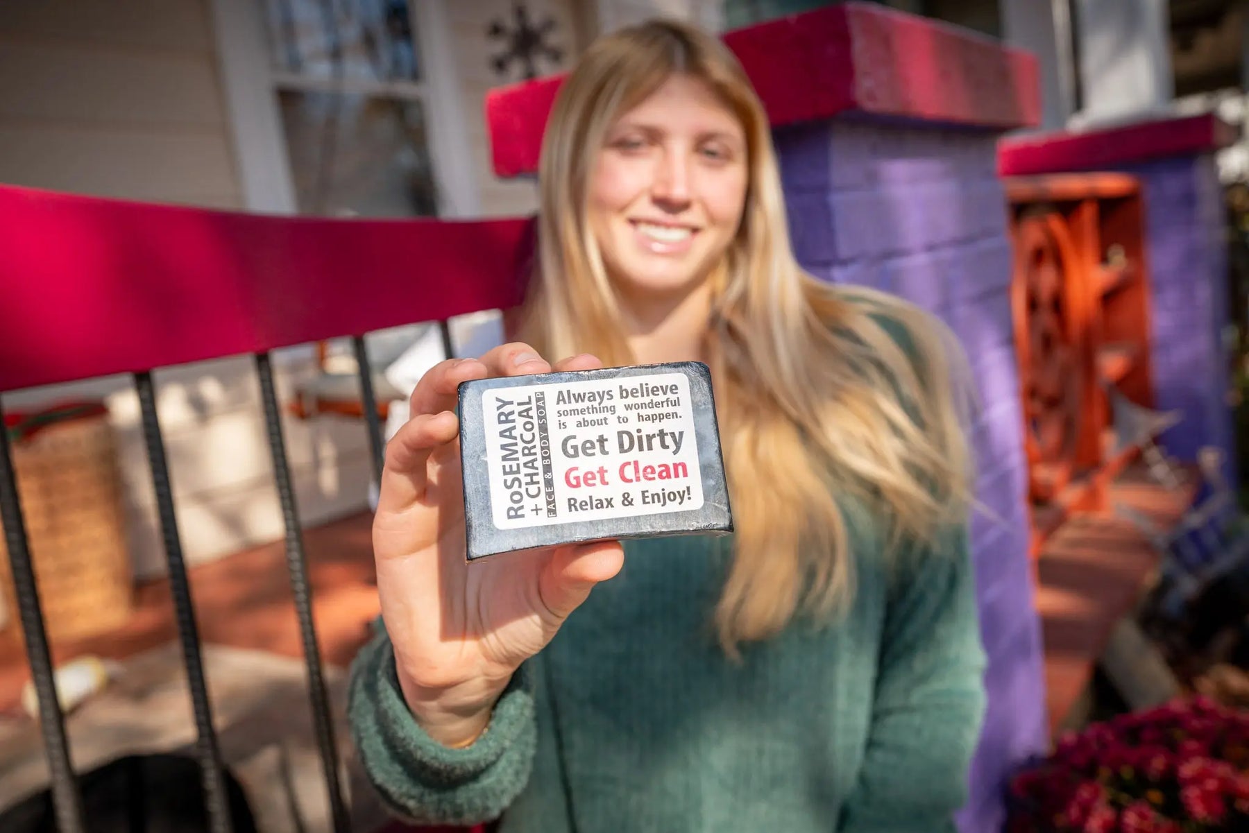 Woman holding a Rosemary + Charcoal face and body soap bar with text on the label.