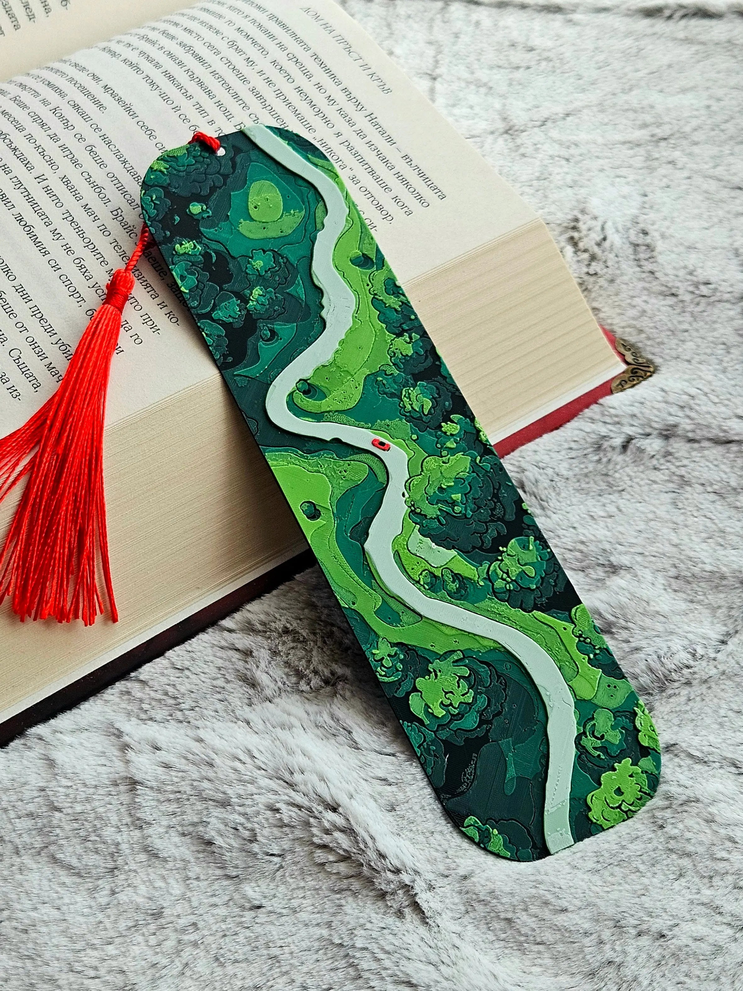 Layered forest road bookmark with a red car and red tassel.