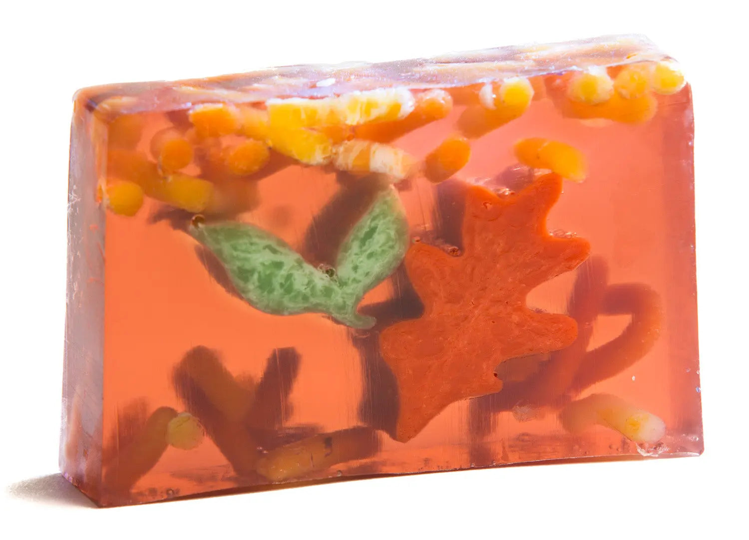 Translucent orange glycerin soap with autumn leaf and fruit inclusions.