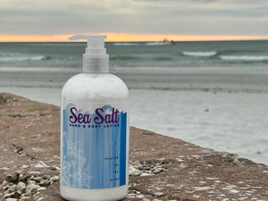 Sea Salt hand and body lotion bottle on a rocky shore with the ocean in the background.