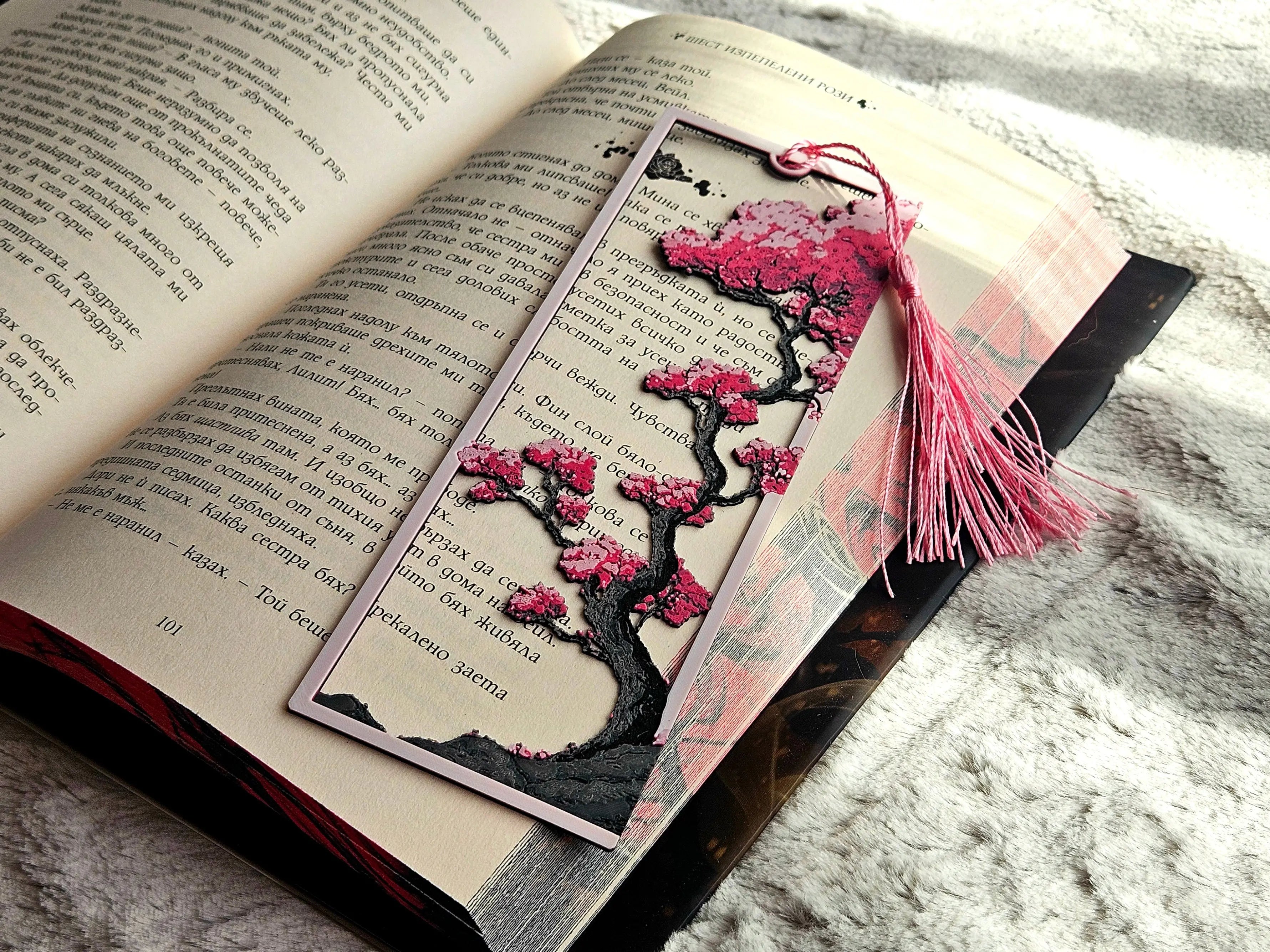 Cherry Blossom Bookmark: Framed bookmark with pink cherry blossoms on a tree design in an open book with a pink tassel.  