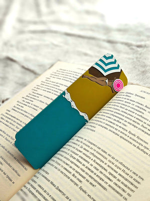 Teal and yellow beach umbrella bookmark in an open book.