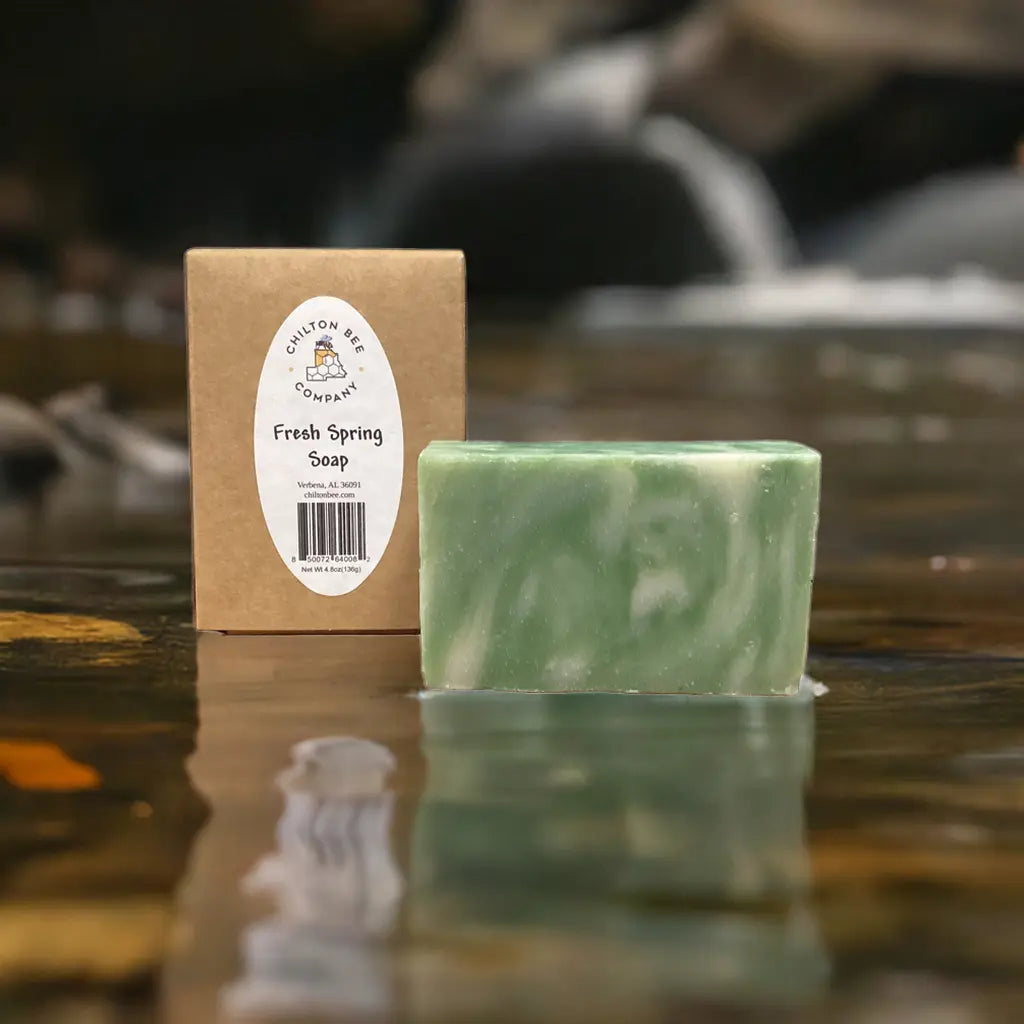 Green and white marbled soap bar with a Chilton Bee Company box, sitting in shallow water.
