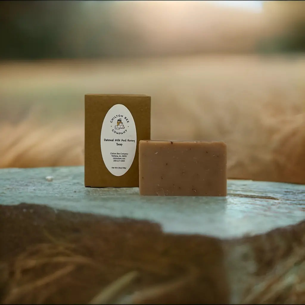 Oatmeal Milk And Honey Soap by Chilton Bee Company next to its brown packaging on a textured surface.