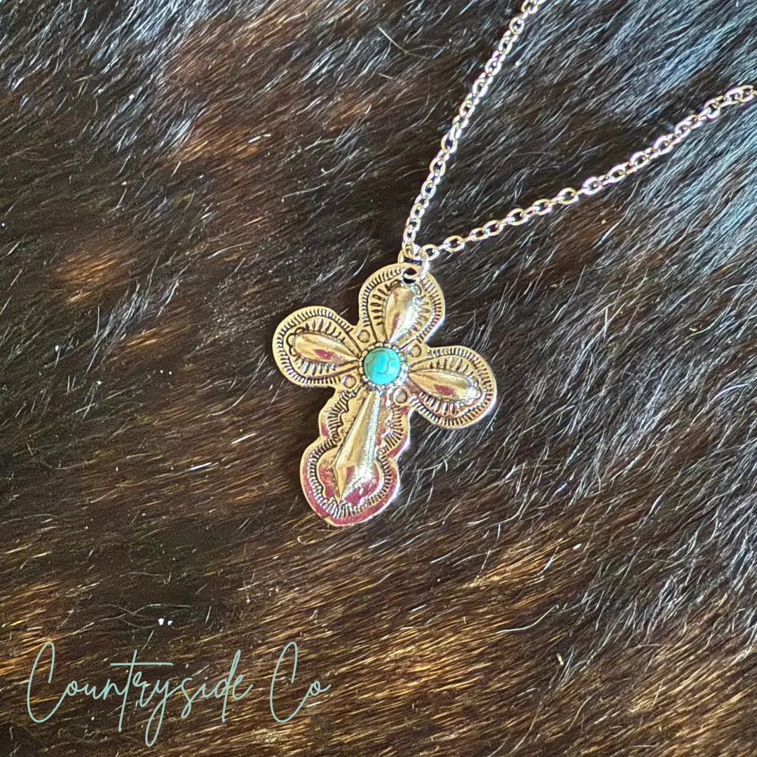 Southwestern cross necklace with turquoise stone on fur background