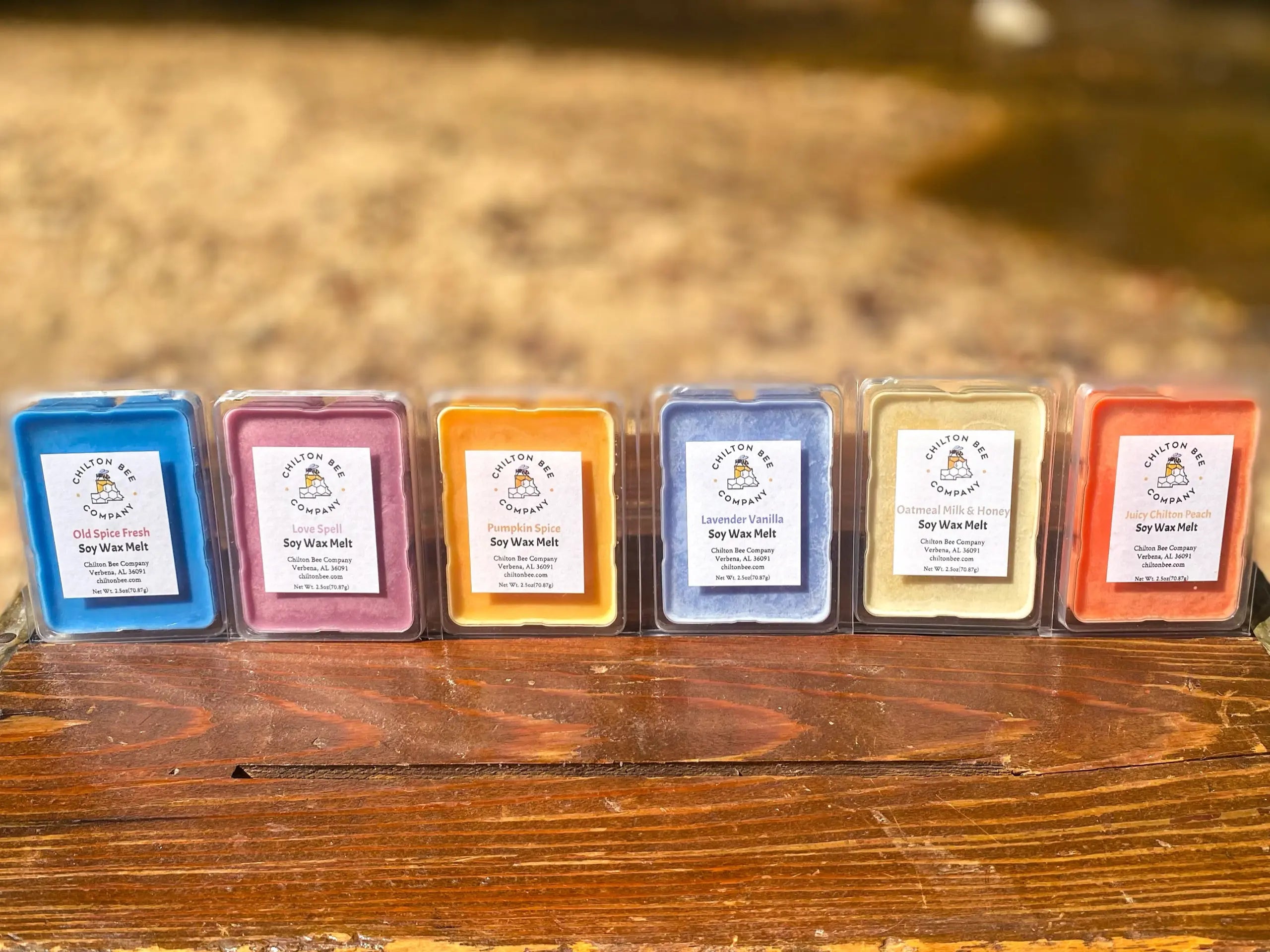 Six colorful Chilton Bee Company soy wax melts in assorted scents, displayed on a wooden surface.