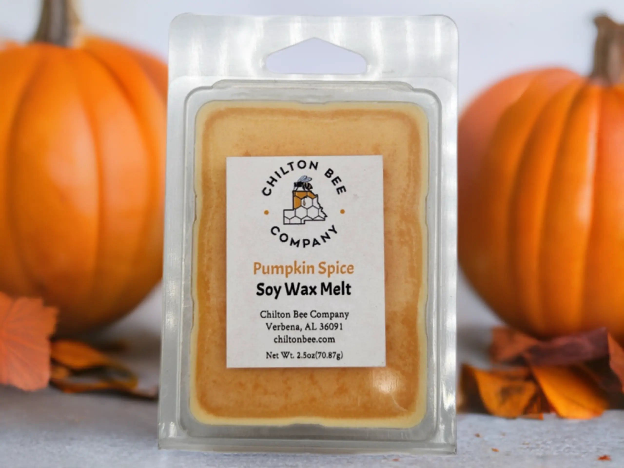Chilton Bee Company Pumpkin Spice soy wax melt in clear packaging with pumpkins in the background and fall leaves around it.
