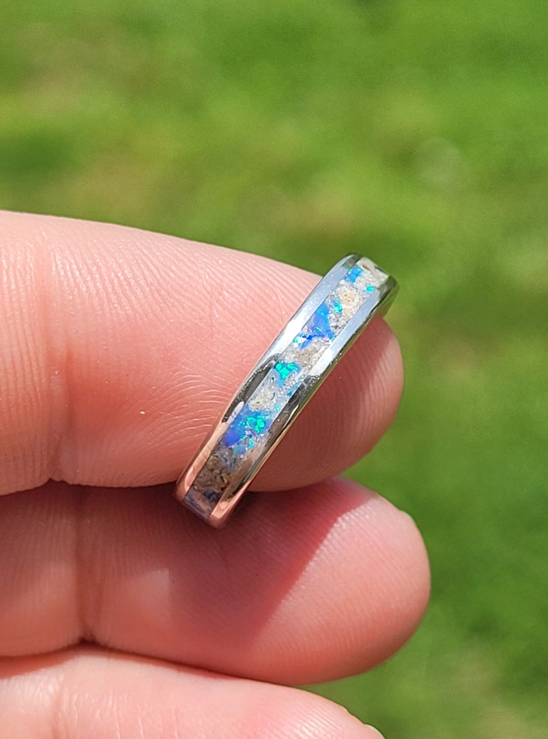 Sterling silver ring with opal inlay and ash, held in hand. Memorial ring with unique design.