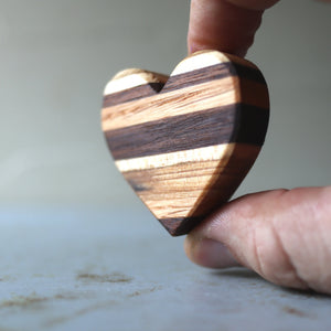 Striped wooden heart made from reclaimed wood with alternating grain patterns.