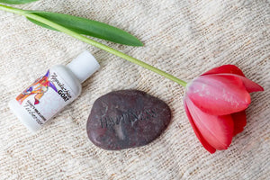 Appalachian Goat Tuberose lotion, red tulip, and 'Happiness' stone on textured fabric.