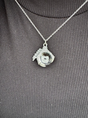 Silver-tone dragon claw necklace with a glass orb pendant on a chain.