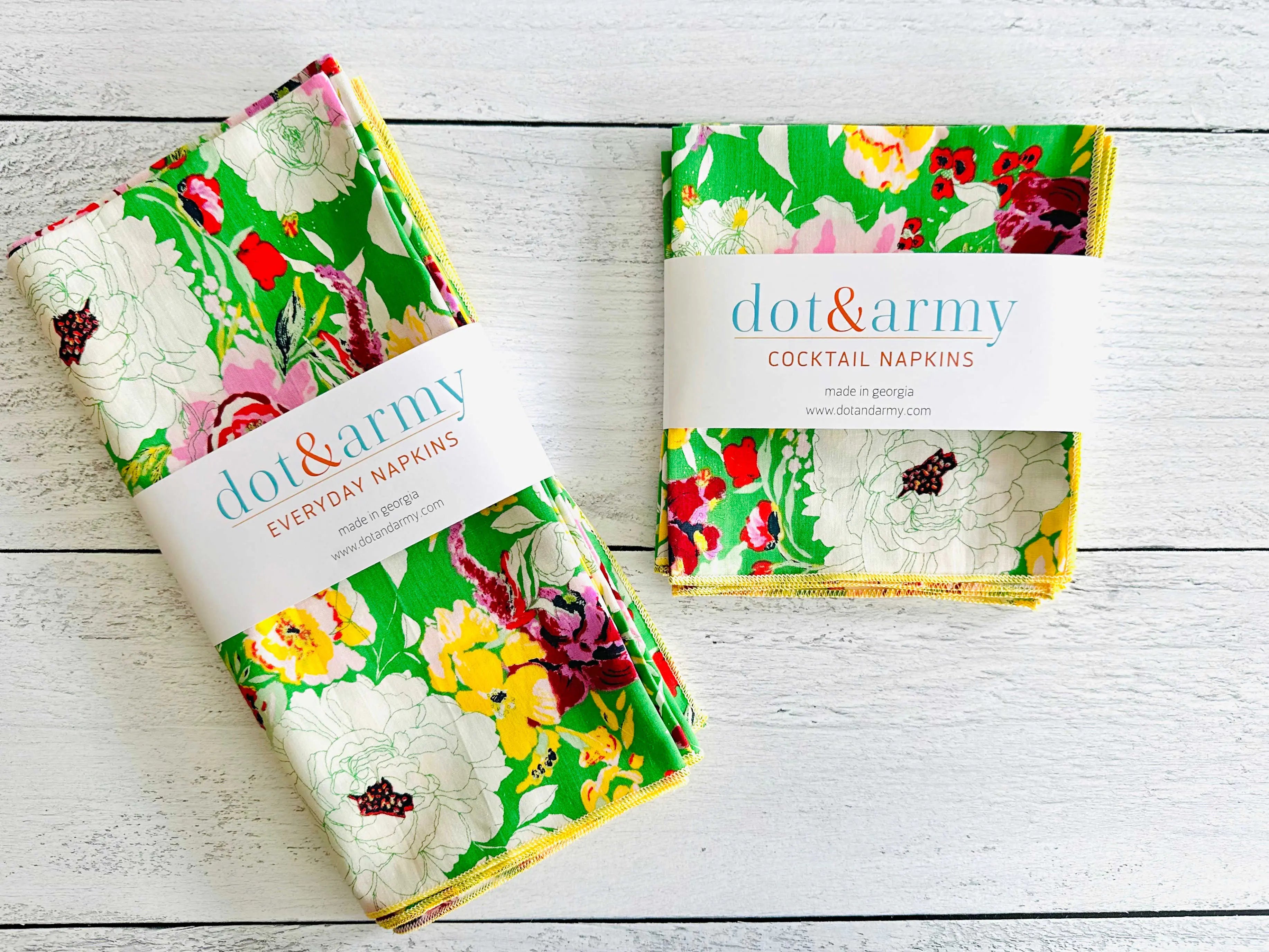 Dot & Army floral cocktail napkins and everyday napkins on a white wooden surface.
