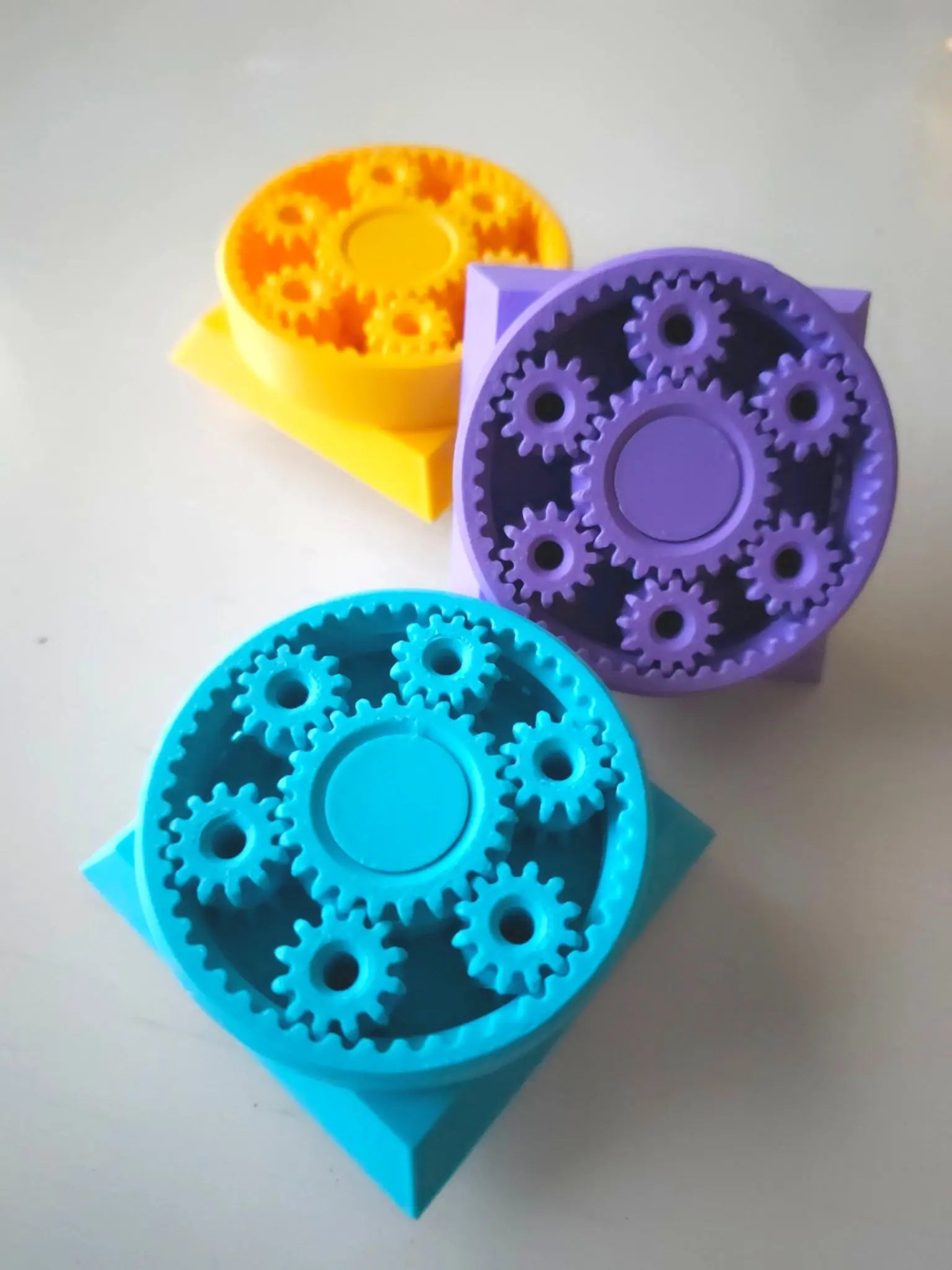 Three colorful fidget gears for a fidget cube on a white surface