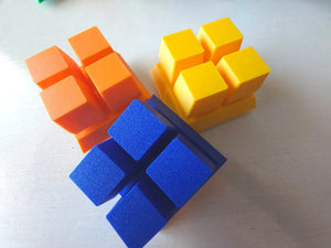Three fidget clicker faces in orange, yellow, and blue on a white surface