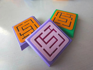 Three square blocks with maze patterns on a light surface