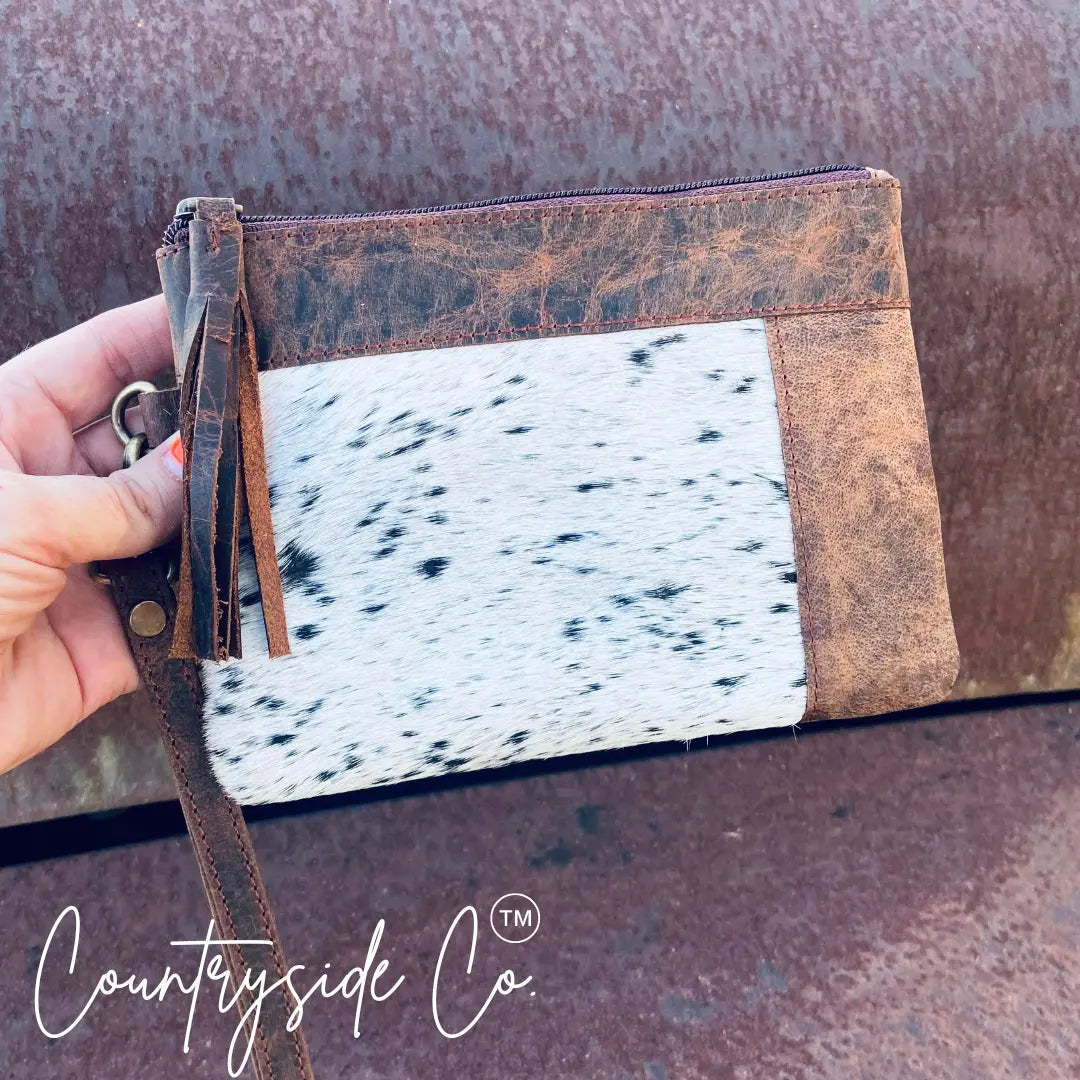 Cowhide leather wristlet with leather trim and tassel.