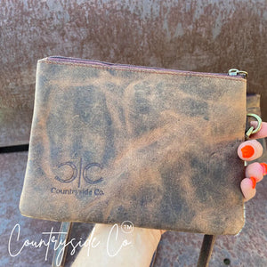 Brown distressed leather wristlet with Countryside Co. logo and orange-tipped fingers.