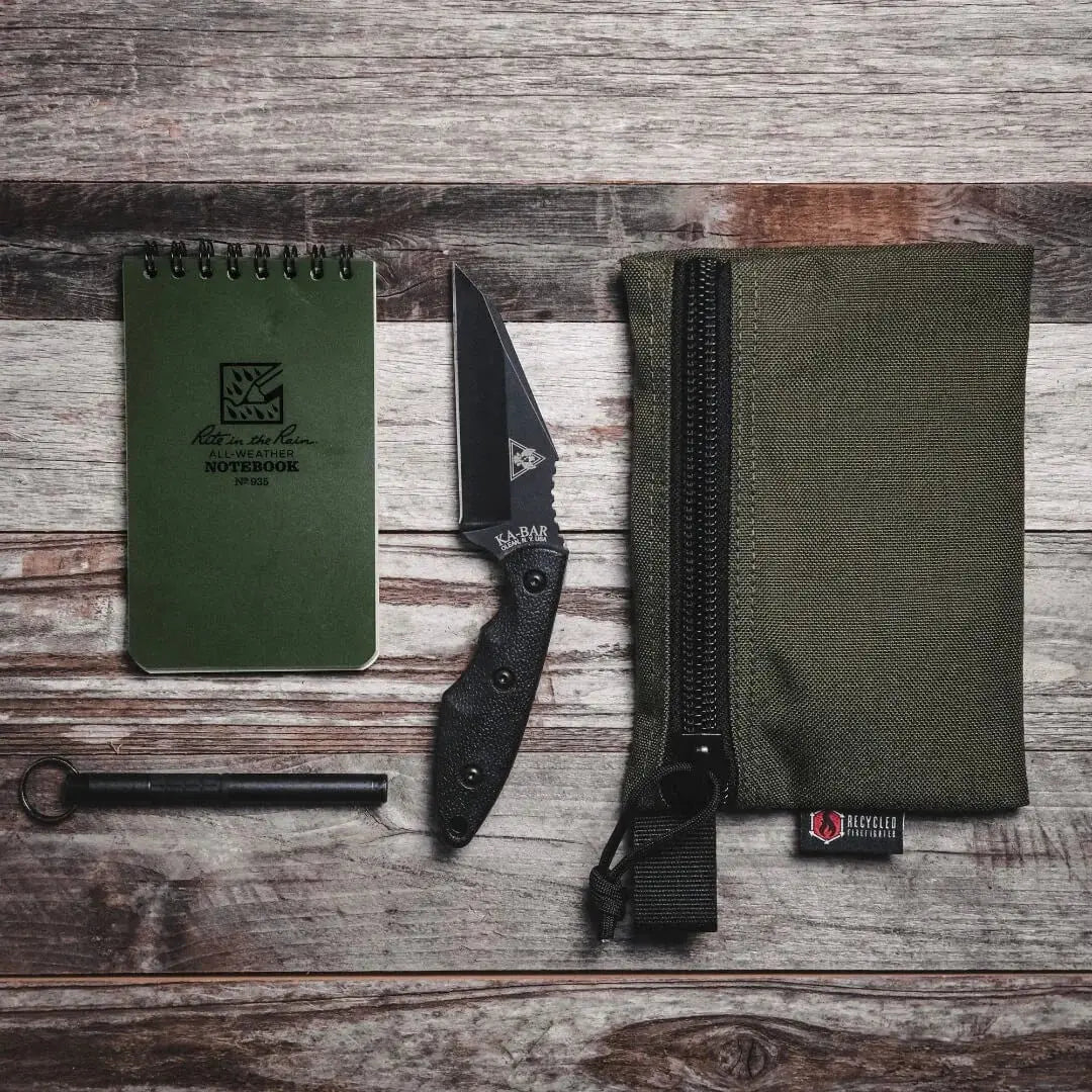 Large green zippered gear pouch with contents on a wooden background.