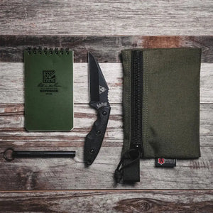 Large green zippered gear pouch with contents on a wooden background.