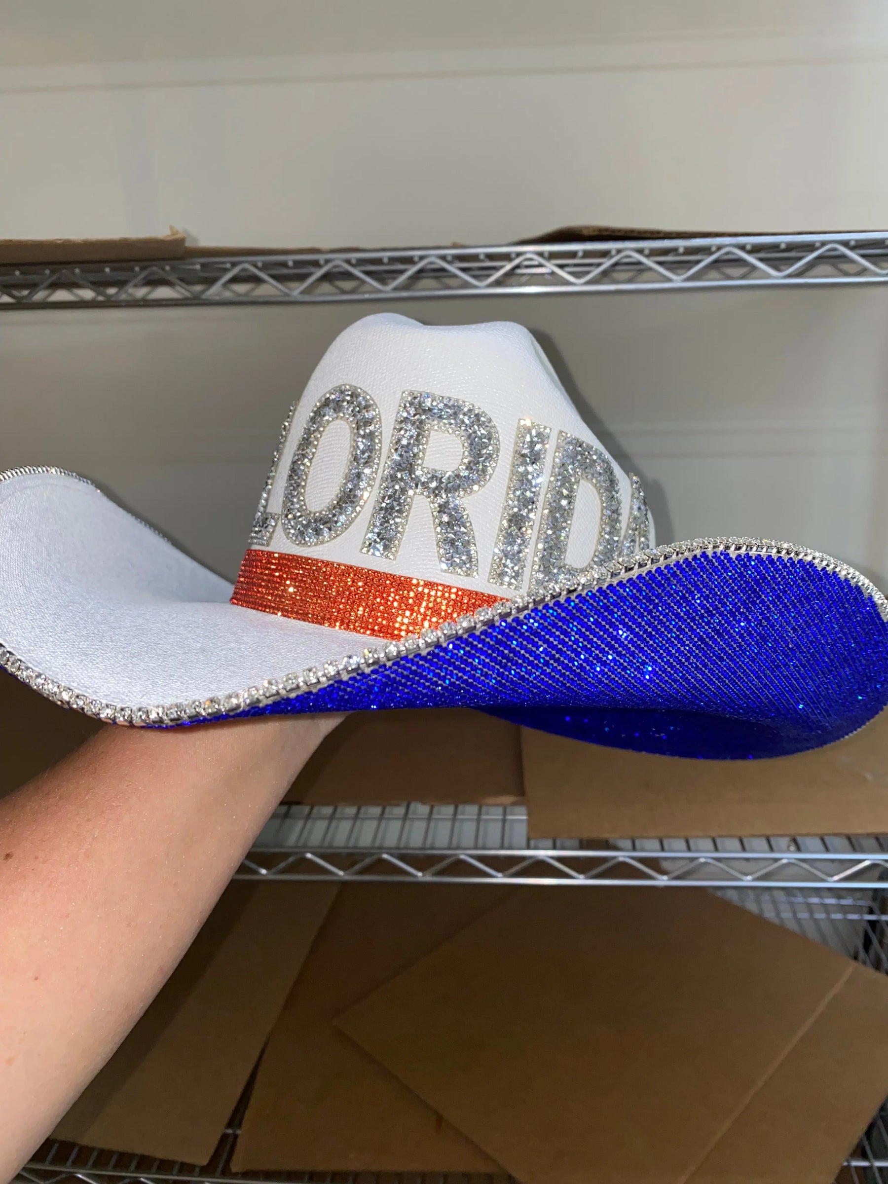 White cowboy hat with "Florida" spelled out in rhinestones, orange band, and blue brim.