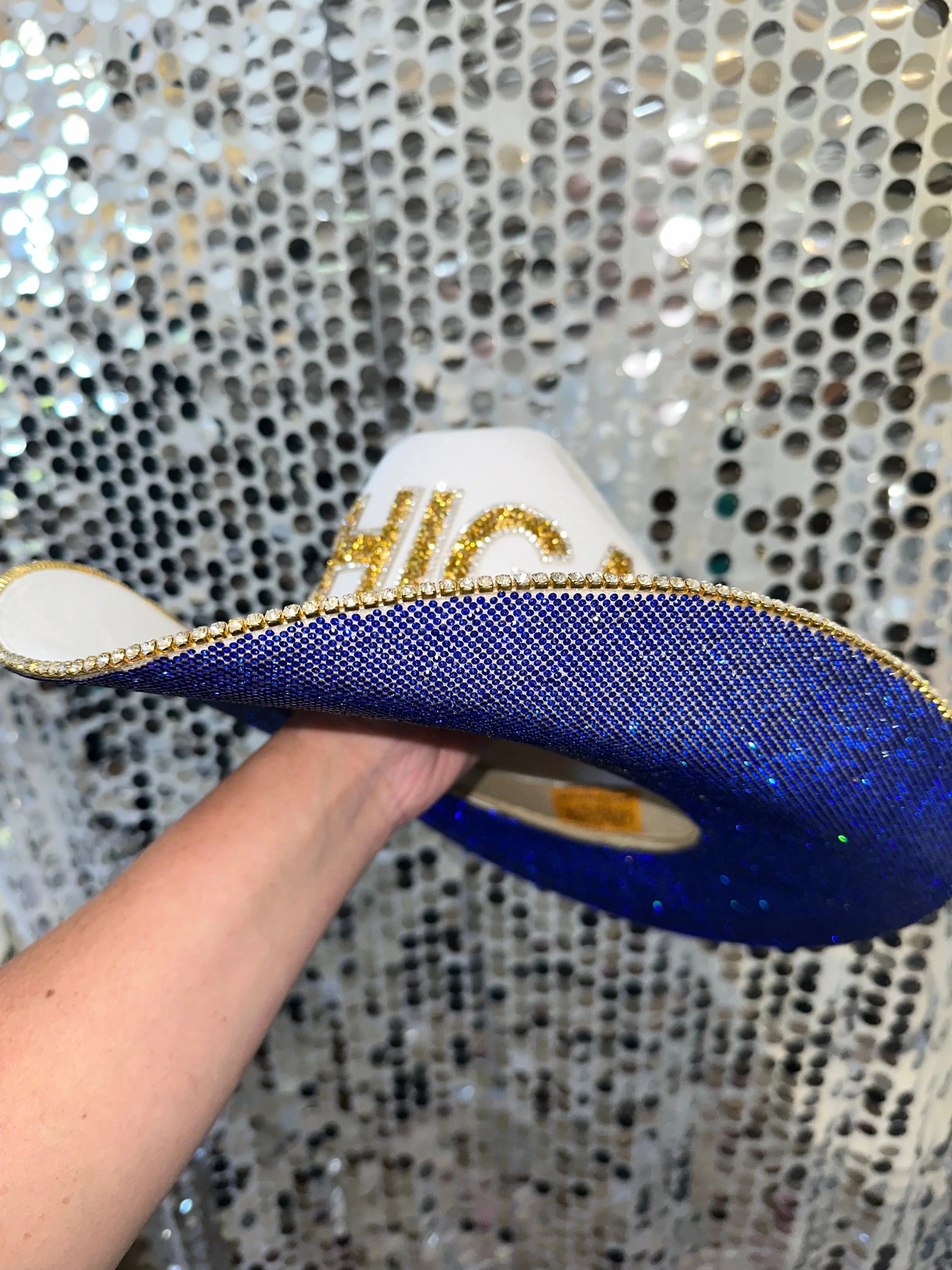 University of Michigan rhinestone cowboy hat with blue and gold accents held by a hand.