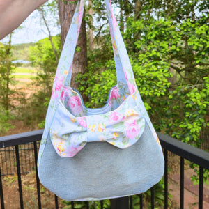 Upcycled denim shoulder bag with a light blue floral bow detail.