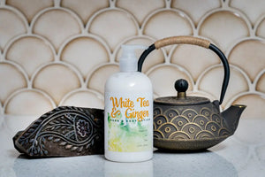White Tea & Ginger hand lotion bottle next to cast iron teapot and carved block.
