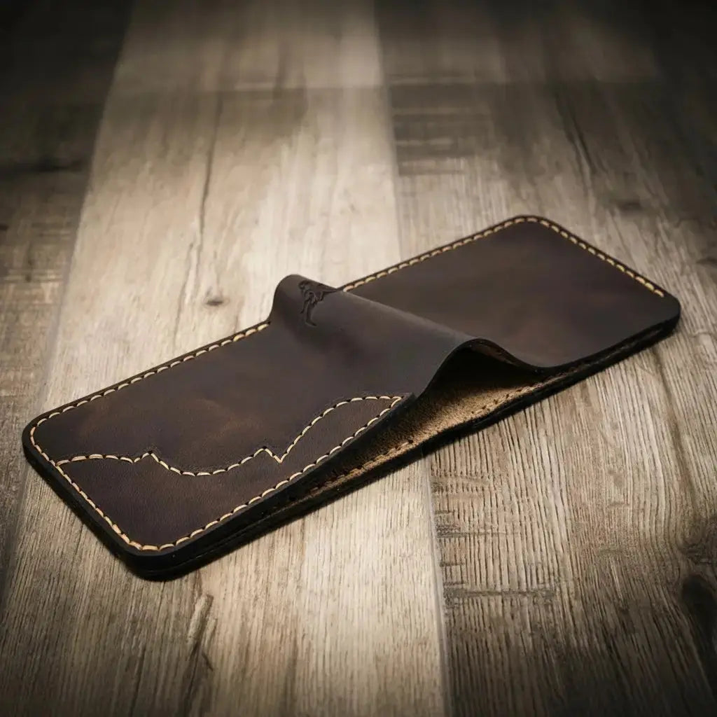 Black hand-stitched leather bifold wallet on a wooden surface.