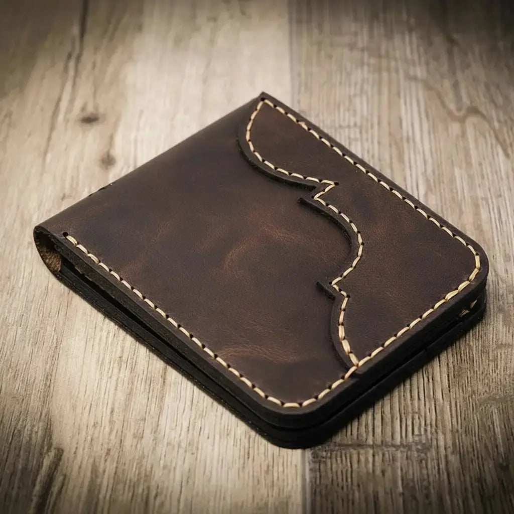 Brown leather bifold wallet with decorative stitching on a wooden surface.