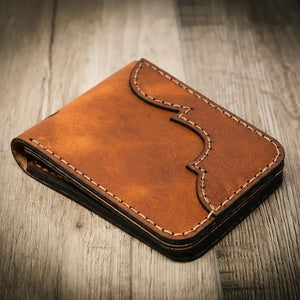 Brown leather bifold wallet with decorative stitching on a wooden surface.