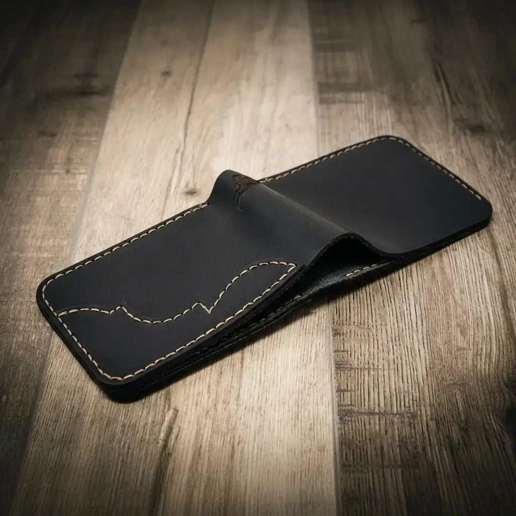 Black leather bifold wallet with Western-style stitching on a wooden surface.