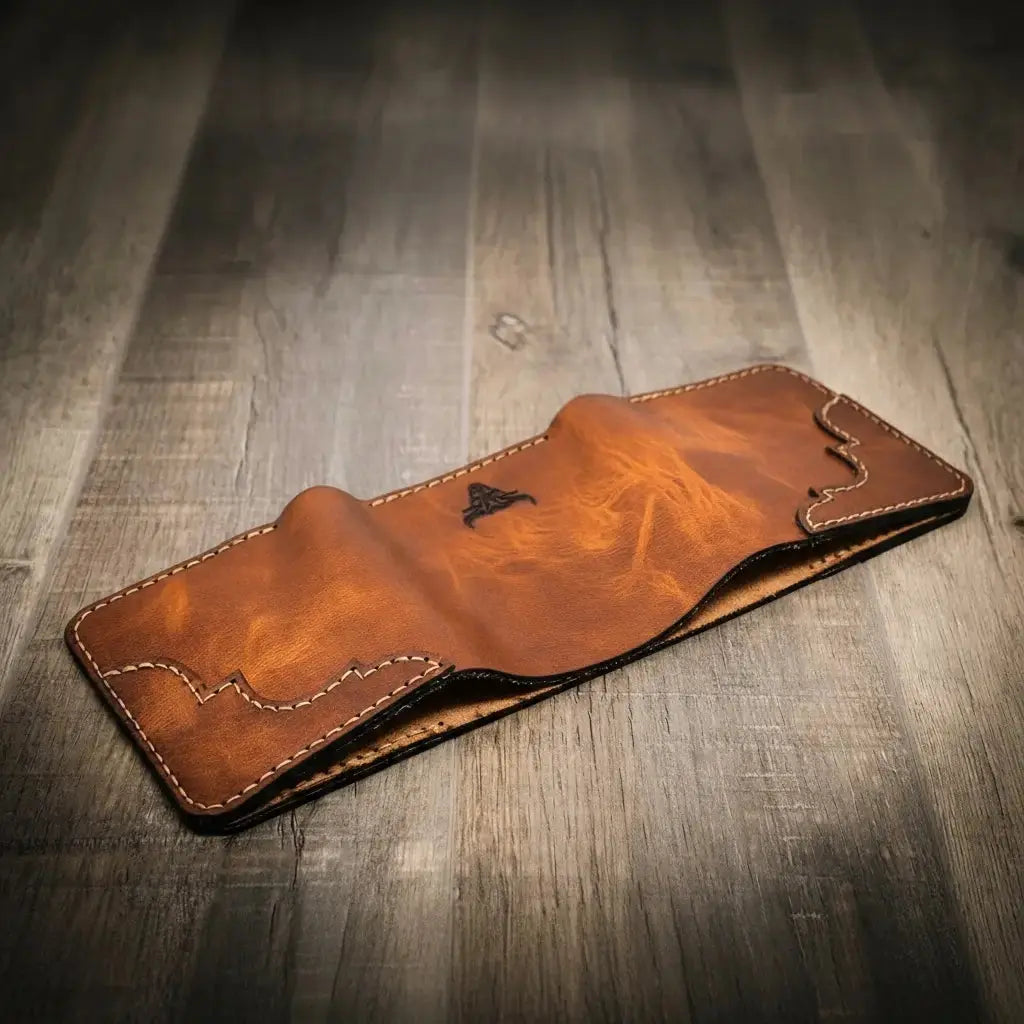 Brown leather bifold wallet with decorative stitching and embossed logo on wooden surface.