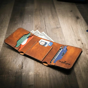 Brown leather trifold wallet holding cards and bills on a wooden surface.