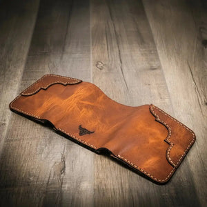 Brown leather trifold wallet open with bull emblem and decorative stitching.