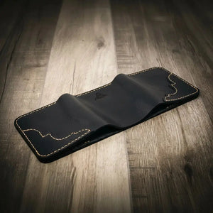 Black leather trifold wallet with stitching on a wooden surface.